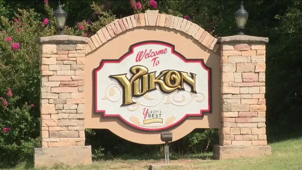 Stone welcome sign with lanterns on pillars reading 'Welcome to Yukon, Yukon's Best'.