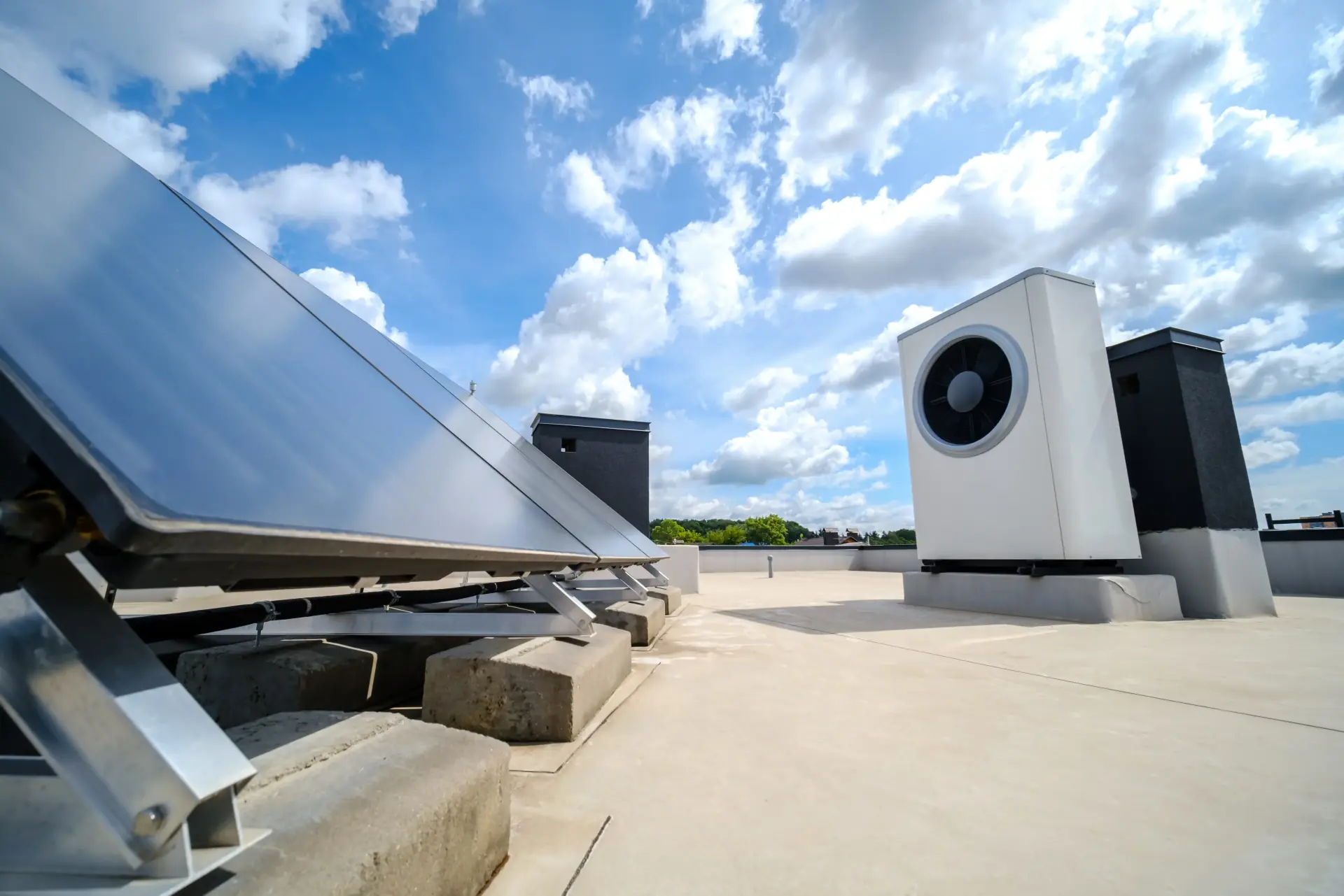 Roof-mounted solar panels alongside a heat pump unit under a partly cloudy blue sky.