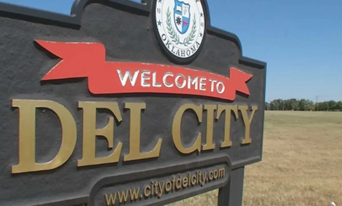 Dark "Welcome to Del City" sign with gold letters, a red banner, and the city seal.