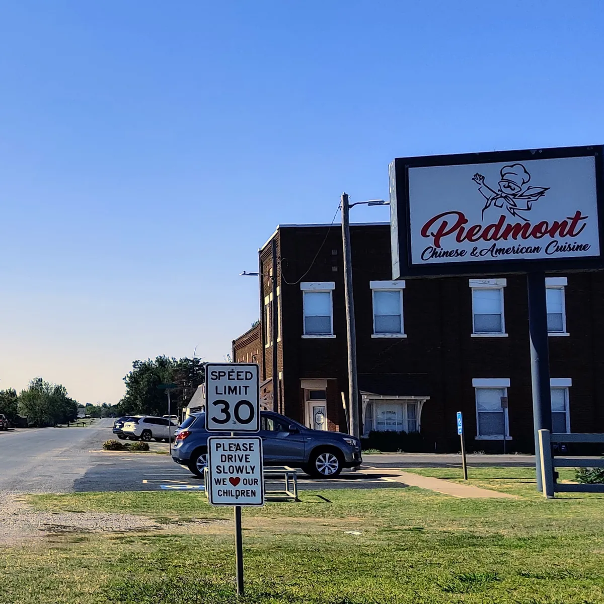Brick buildings and a Piedmont sign along a quiet street in old downtown Piedmont, Oklahoma.