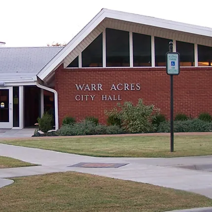 Brick Warr Acres City Hall building with a landscaped lawn and walkway in Warr Acres, Oklahoma.