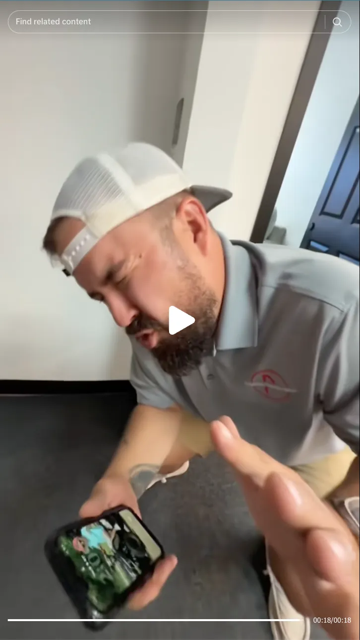 Roofing by Prodigy - Man wearing a white mesh cap and gray polo shirt intensely reacting while holding a smartphone.